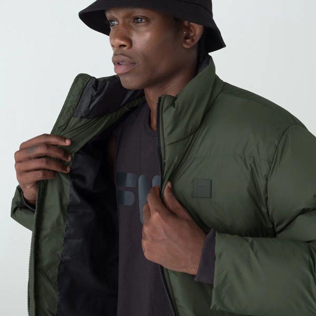 A Jaqueta Masculina Fila Round é a escolha ideal para os dias mais frios. Confeccionada em matelassê de poliéster com modelagem puffer, oferece isolamento térmico e conforto inigualável.