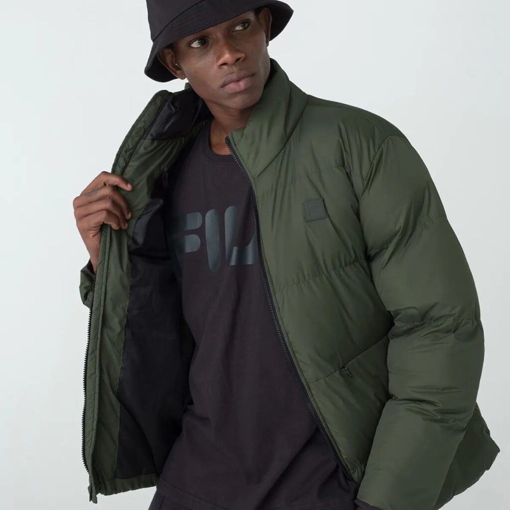 A Jaqueta Masculina Fila Round é a escolha ideal para os dias mais frios. Confeccionada em matelassê de poliéster com modelagem puffer, oferece isolamento térmico e conforto inigualável.
