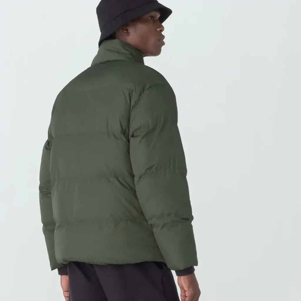 A Jaqueta Masculina Fila Round é a escolha ideal para os dias mais frios. Confeccionada em matelassê de poliéster com modelagem puffer, oferece isolamento térmico e conforto inigualável.