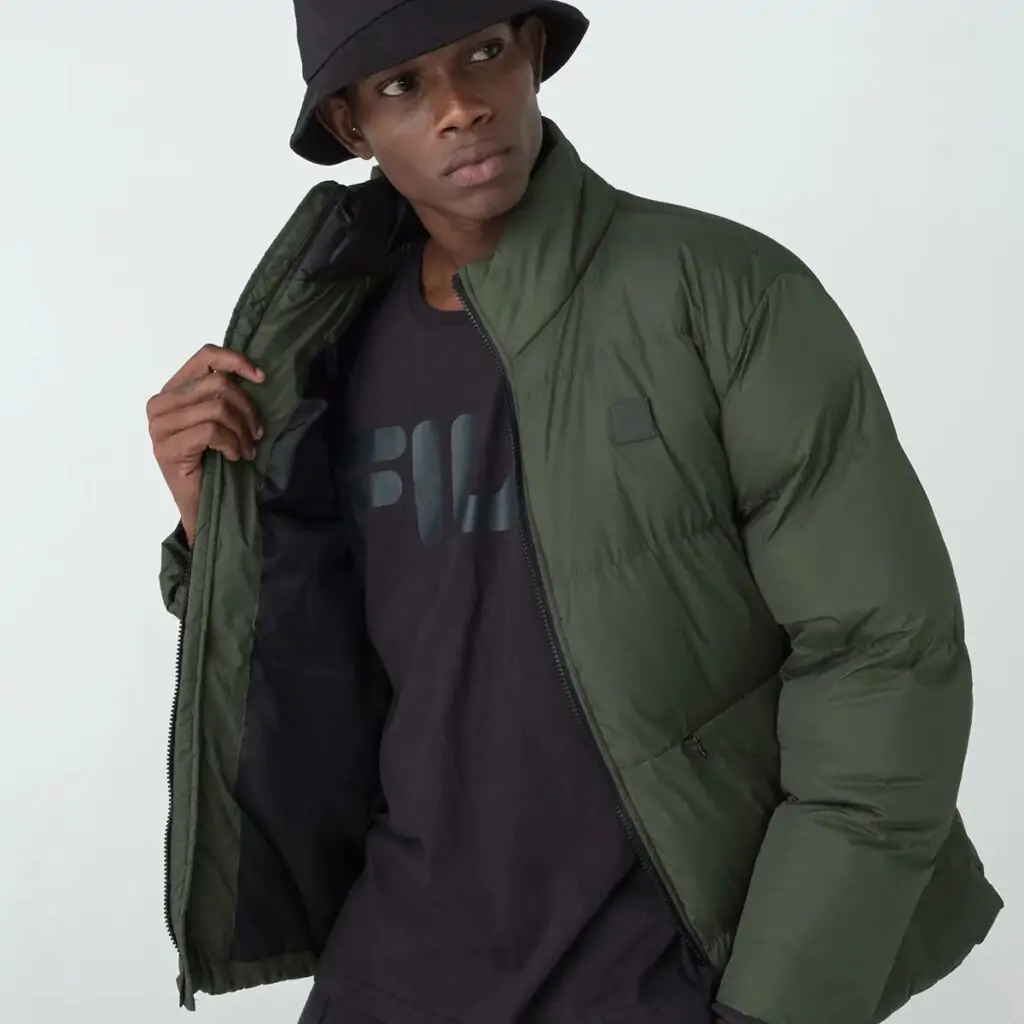 A Jaqueta Masculina Fila Round é a escolha ideal para os dias mais frios. Confeccionada em matelassê de poliéster com modelagem puffer, oferece isolamento térmico e conforto inigualável.